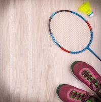 Sportausrüstung mit Badmintonschlägern und Turnschuhen auf Holzhintergrund foto