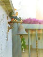 kleine Eisenglocke mit farbigem Hahn vor dem Haus. foto
