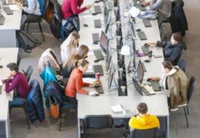 Blured Student für den Computer in der Bibliothek foto