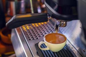 Kaffeetasse Espresso aus der Kaffeemaschine gießen. professionelle Kaffeezubereitung im Café foto