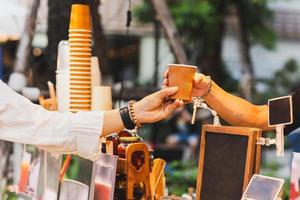 mann barista serviert heißen kaffee in pappbecher an kunden über theke im café im freien. foto