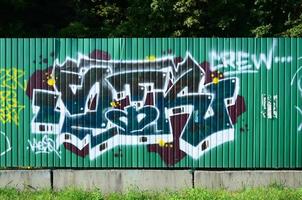 Fragment von Graffiti-Zeichnungen. Die alte Wand ist mit Farbflecken im Stil der Straßenkunstkultur dekoriert. farbige Hintergrundtextur in Grüntönen foto