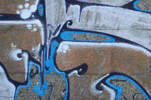 Fragment von Graffiti-Zeichnungen. Die alte Wand ist mit Farbflecken im Stil der Straßenkunstkultur dekoriert. farbige Hintergrundtextur in warmen Tönen foto