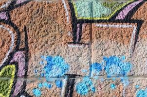 Fragment von Graffiti-Zeichnungen. Die alte Wand ist mit Farbflecken im Stil der Straßenkunstkultur dekoriert. farbige Hintergrundtextur in warmen Tönen foto