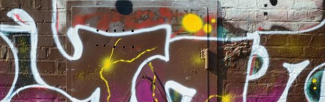 Fragment von Graffiti-Zeichnungen. Die alte Wand ist mit Farbflecken im Stil der Straßenkunstkultur dekoriert. farbige Hintergrundtextur in warmen Tönen foto