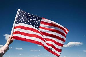 US-Flagge in der Hand gegen den blauen Himmel schwenken foto