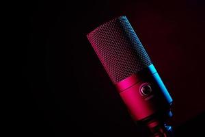studiomikrofon auf dunklem hintergrund mit neonlichtern foto