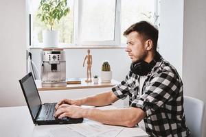 Mann arbeitet aus der Ferne im Home Office mit Laptop foto