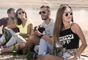 sommer, ferien, urlaub, musik, fröhliches menschenkonzept - gruppe von freunden mit gitarre, die spaß am strand haben foto