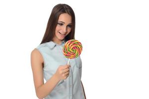 Frau leckt süße Süßigkeiten. weibliches Modell, das köstlichen Süßwarenlutscher mit überraschtem Ausdruck isst. Studioaufnahme isolierter weißer Hintergrund foto