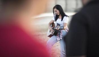 Porträt einer jungen Frau, die am Lagerfeuer am See Gitarre spielt foto