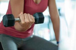 Die Hand der Frau hebt die Hantel an, um die Armmuskulatur zu straffen. Übung in einem Fitness-Center oder Haus. foto