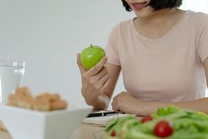 Frauen mit schlankem Körper wählen gesunde Lebensmittel und Junk Food, Frauen wählen grünen Apfel für die Ernährung. gutes gesundes essen. Gewicht verlieren, Gleichgewicht halten, kontrollieren, Fett reduzieren, wenig Kalorien, Routinen, Bewegung.