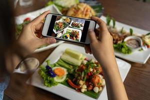 Frau fotografiert eine Mahlzeit auf dem Tisch, nachdem sie online Essen bestellt hat, um es zu Hause zu essen. fotografieren und telefonkonzepte verwenden foto