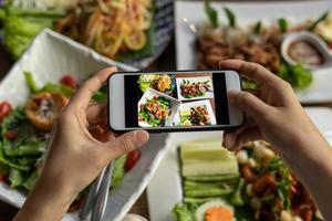 Frau fotografiert eine Mahlzeit auf dem Tisch, nachdem sie online Essen bestellt hat, um es zu Hause zu essen. fotografieren und telefonkonzepte verwenden foto