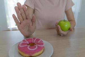 Frauen mit schlankem Körper wählen gesunde Lebensmittel und Junk Food, Frauen wählen grünen Apfel für die Ernährung. gutes gesundes essen. Gewicht verlieren, Gleichgewicht halten, kontrollieren, Fett reduzieren, wenig Kalorien, Routinen, Bewegung. foto