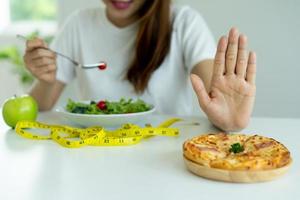 Frauen lehnen Junk Food oder ungesunde Lebensmittel wie Donuts ab und wählen gesunde Lebensmittel wie grüne Äpfel und Salate. konzept des fastens und der guten gesundheit. foto