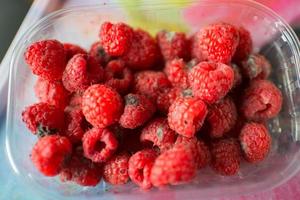 Plastikbehälter mit Himbeeren in schlechtem Zustand foto