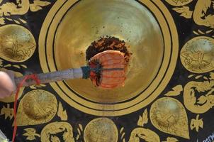 Halten Sie einen Holzhammer, um die Glocke des großen Kreises im buddhistischen Tempel zu schlagen, alte thailändische kulturelle Überzeugungen foto