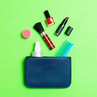 Make-up-Produkte, die aus der Kosmetiktasche auf grünem Hintergrund mit leerem Raum für Ihr Design verschüttet werden foto