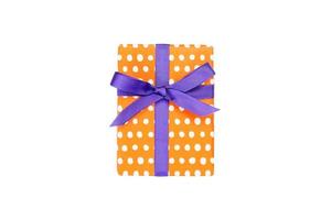 Weihnachten oder andere Feiertage handgemachtes Geschenk in orangefarbenem Papier mit lila Schleife. isoliert auf weißem Hintergrund, Ansicht von oben. Thanksgiving-Geschenkbox-Konzept foto