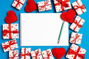 Blick von oben auf das Notizbuch, umgeben von Geschenkboxen und Herzen auf buntem Hintergrund. Valentinstag-Konzept foto