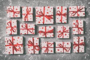 Draufsicht auf verschiedene Geschenkboxen. Eingewickelter Valentinsgruß oder ein anderes handgemachtes Weihnachtsgeschenk in Papier mit rotem Band und Herz. Präsentkarton, Dekoration des Geschenks auf Holztisch. getöntes Vintage-Bild foto