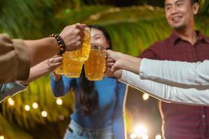 gruppe glücklicher freunde, die bier auf einem party-hinterhof trinken und anstoßen foto