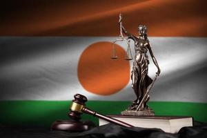 Niger-Flagge mit Statue der Justitia, Verfassung und Richterhammer auf schwarzem Vorhang. Begriff von Urteil und Schuld foto