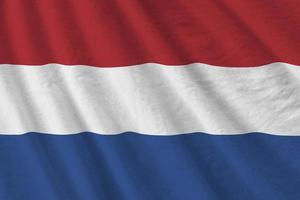 niederländische flagge mit großen falten, die im innenbereich unter dem studiolicht wehen. die offiziellen symbole und farben im banner foto
