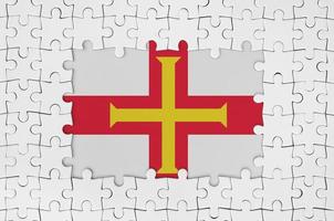 Guernsey-Flagge im Rahmen aus weißen Puzzleteilen mit fehlendem Mittelteil foto