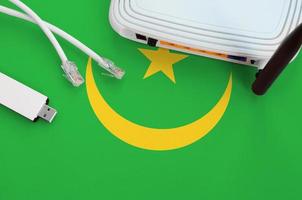 Mauretanien-Flagge auf dem Tisch mit Internet-RJ45-Kabel, drahtlosem USB-WLAN-Adapter und Router. Konzept der Internetverbindung foto