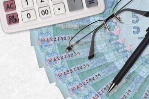 5 ukrainische hryvnias Rechnungen Fan und Taschenrechner mit Brille und Stift. Konzept für Geschäftsdarlehen oder Steuerzahlungssaison foto