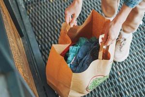 junge frau mit alten kleidern an der empfangsstelle der materialien für das recycling foto