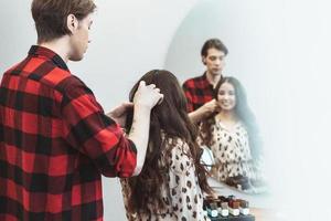 stylist friseur stylen lange haare für schöne asiatische junge frau im schönheitssalon, arbeitsmoment