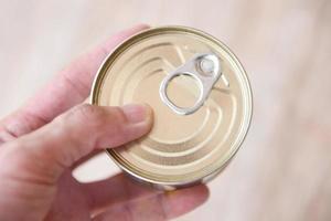 konserven metalldosen in der hand - konserven haltbare lebensmittel lagerware in der küche zu hause oder für spenden foto