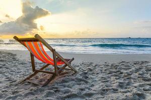 Stuhl Strand auf Sand in den Sommerferien Natur Reisen schöne Sommerlandschaft mit - tropischen Urlaub Sonnenuntergang oder Sonnenaufgang am Strand mit Meer und gelben Himmel Ozean Hintergrund foto