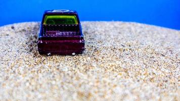 minahasa, indonesien montag, 12. dezember 2022, spielzeugauto auf dem sand auf blauem hintergrund foto