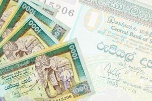 1000 Sri-Lanka-Rupien-Scheine liegen im Stapel auf dem Hintergrund einer großen halbtransparenten Banknote. abstrakter betriebswirtschaftlicher hintergrund foto