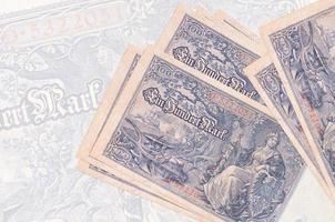 100 Reichsmarkscheine liegen im Stapel auf dem Hintergrund einer großen halbtransparenten Banknote. abstrakte Darstellung der Landeswährung foto