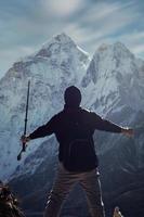 eine silhouette eines mannes in nepal überblickt den ama dablam berg im dorf dingboche in den blauen und bewölkten himmel mit einem großen schneebedeckten berg. foto