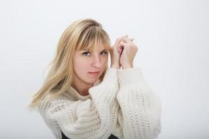 Schließen Sie herauf Porträt des blonden Mädchenmodells im weißen Wollpullover auf weißem Hintergrund im Studio foto