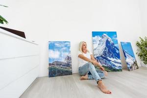 glückliche blonde frau, die zu hause ein großes bild an der wand hängt foto