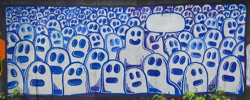 die alte Mauer, gemalt in Graffiti-Farbzeichnung mit Aerosolfarben. das Bild einer Reihe identischer Cartoon-Gesichter als Konzept einer sinnlosen Menge mit einem herausragenden Charakter und einer Wolke für die Rede
