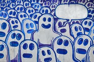 die alte Mauer, gemalt in Graffiti-Farbzeichnung mit Aerosolfarben. das Bild einer Reihe identischer Cartoon-Gesichter als Konzept einer sinnlosen Menge mit einem herausragenden Charakter und einer Wolke für die Rede foto