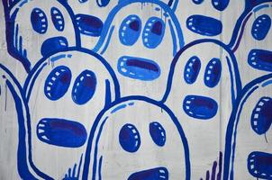 die alte Mauer, gemalt in Graffiti-Farbzeichnung mit Aerosolfarben. das Bild einer Reihe identischer Cartoon-Gesichter. das Konzept einer geistlosen Masse