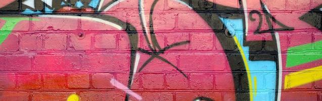 abstraktes buntes fragment von graffiti-gemälden auf alter backsteinmauer. Straßenkunstkomposition mit Teilen ungeschriebener Buchstaben und mehrfarbiger Flecken. subkulturelle Hintergrundtextur foto
