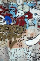Nahaufnahmefragment einer Graffiti-Zeichnung, die mit Aerosolfarbe auf die Wand aufgetragen wurde. Die Wand ist mit einer Vielzahl bunter Unterschriften und Tags von Straßenkünstlern und Hooligans verwöhnt foto