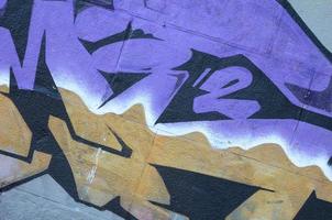 Fragment von Graffiti-Zeichnungen. Die alte Wand ist mit Farbflecken im Stil der Straßenkunstkultur dekoriert. farbige Hintergrundtextur in violetten Tönen foto