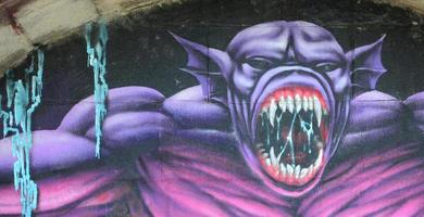 Fragment von Graffiti-Zeichnungen. Die alte Wand ist mit Farbflecken im Stil der Straßenkunstkultur dekoriert. Lila gruseliges Monster foto